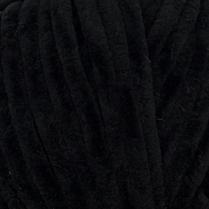 A close-up of thick black yarn strands, showing the soft texture and ribbed pattern of the fiber.