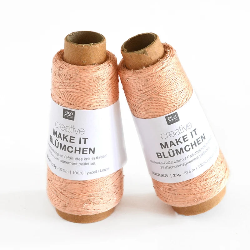 Two cones of Rico Design Creative Make It Blümchen thread in a light peach-pink color, standing upright against a plain white background.