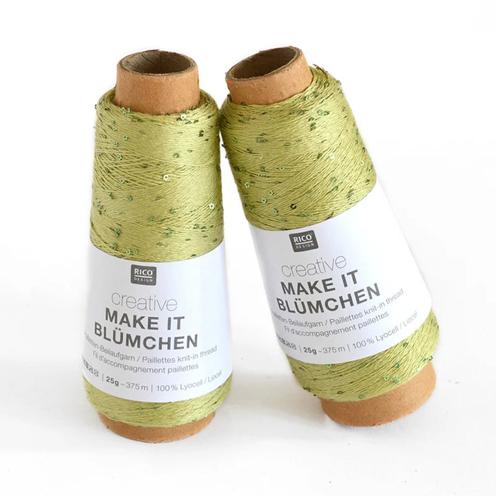 Two cones of Rico Design Creative Make It Blümchen thread in a light olive green color with subtle sequins, displayed on a clean white background.
