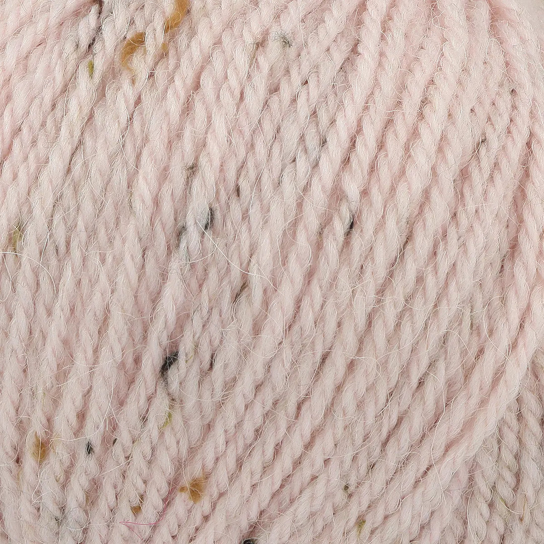 Close-up of pink yarn with speckles, showing texture and color.