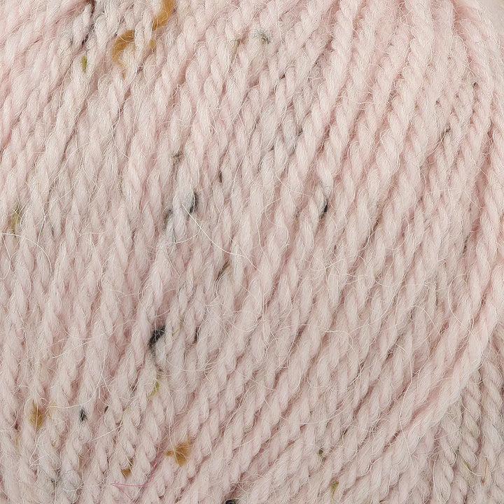 Close-up of pink yarn with speckles, showing texture and color.