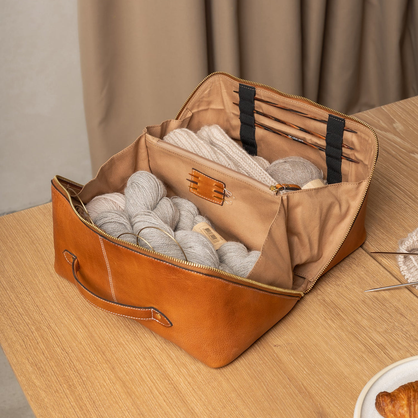 Brown leather bag with yarn inside on a wooden surface
