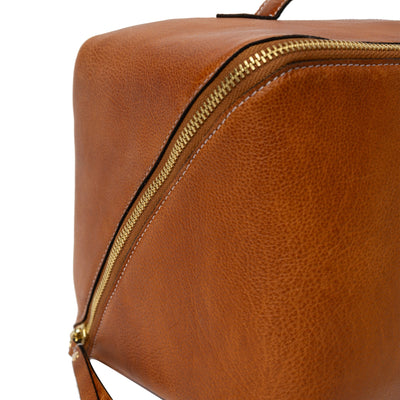 Brown leather dopp kit with gold zipper on a white background