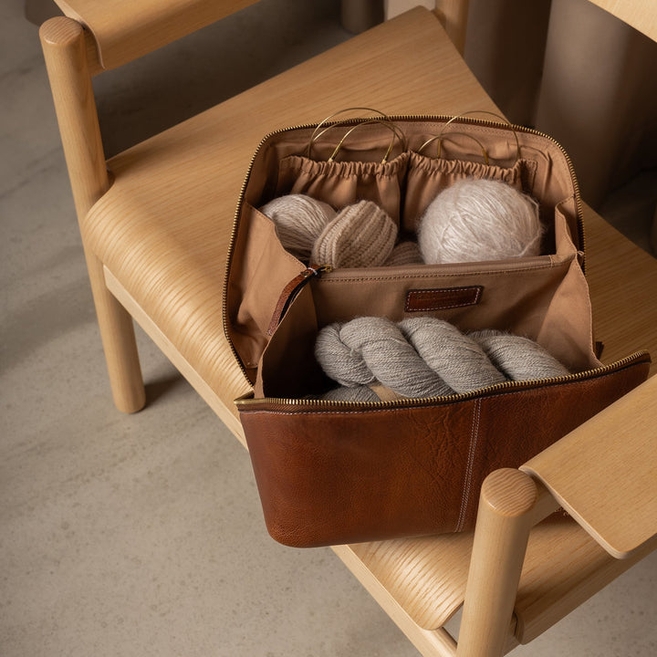 Brown leather bag with yarn on a wooden chair