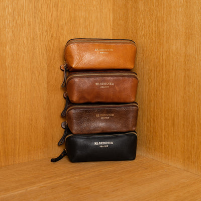 Stack of leather pouches in brown and black on a wooden shelf