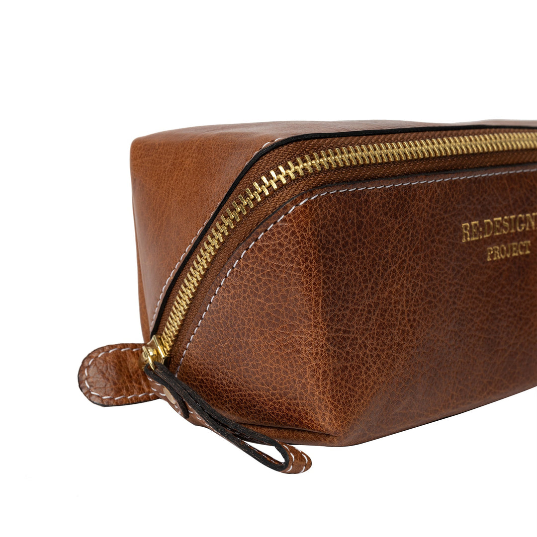 Brown leather toiletry bag with gold zipper on a white background