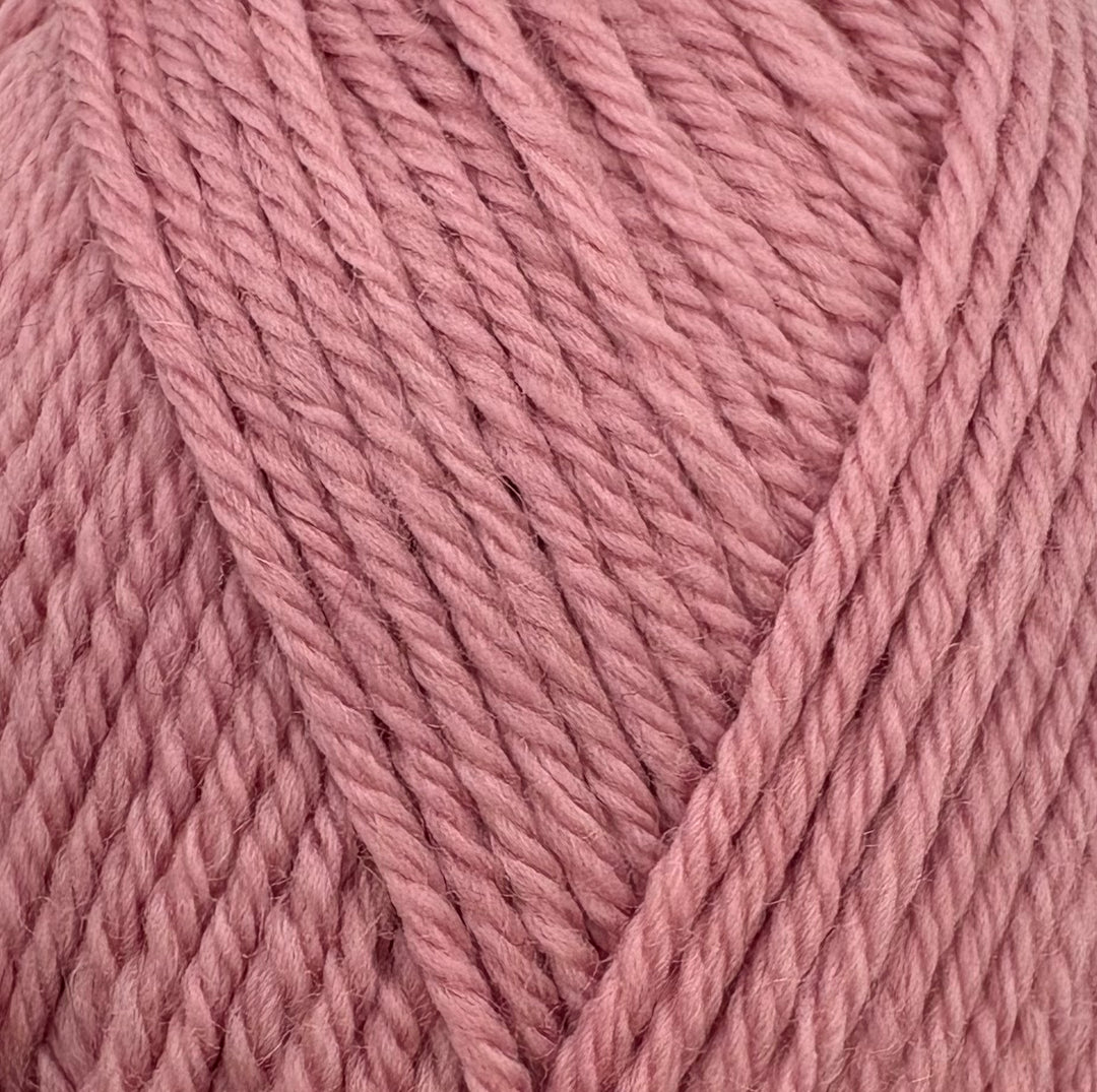 A close-up of dusty pink yarn strands arranged in a V-shape pattern, showing the texture and color of the wool or acrylic fiber.