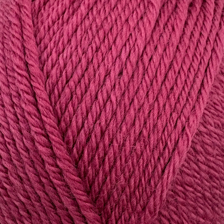 A close-up of bright pink yarn with a twisted plied texture, filling the entire frame.