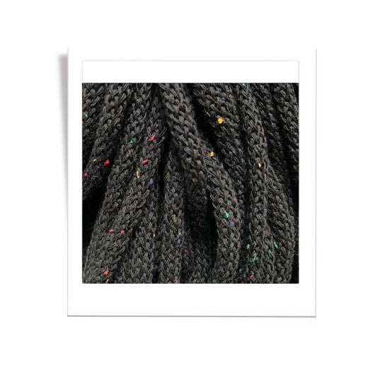 Close-up of black braided yarn with speckled pattern on a white background