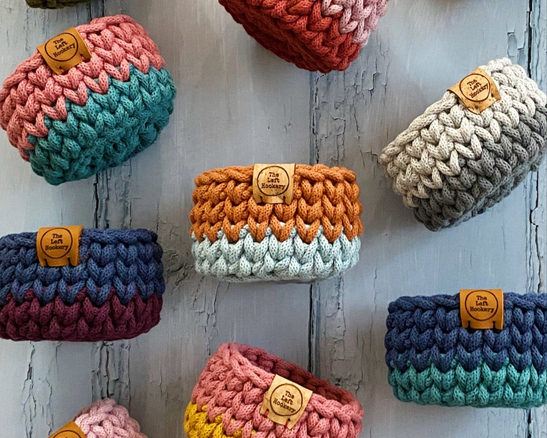 tiny brightly coloured two tone crochet baskets on a blue background