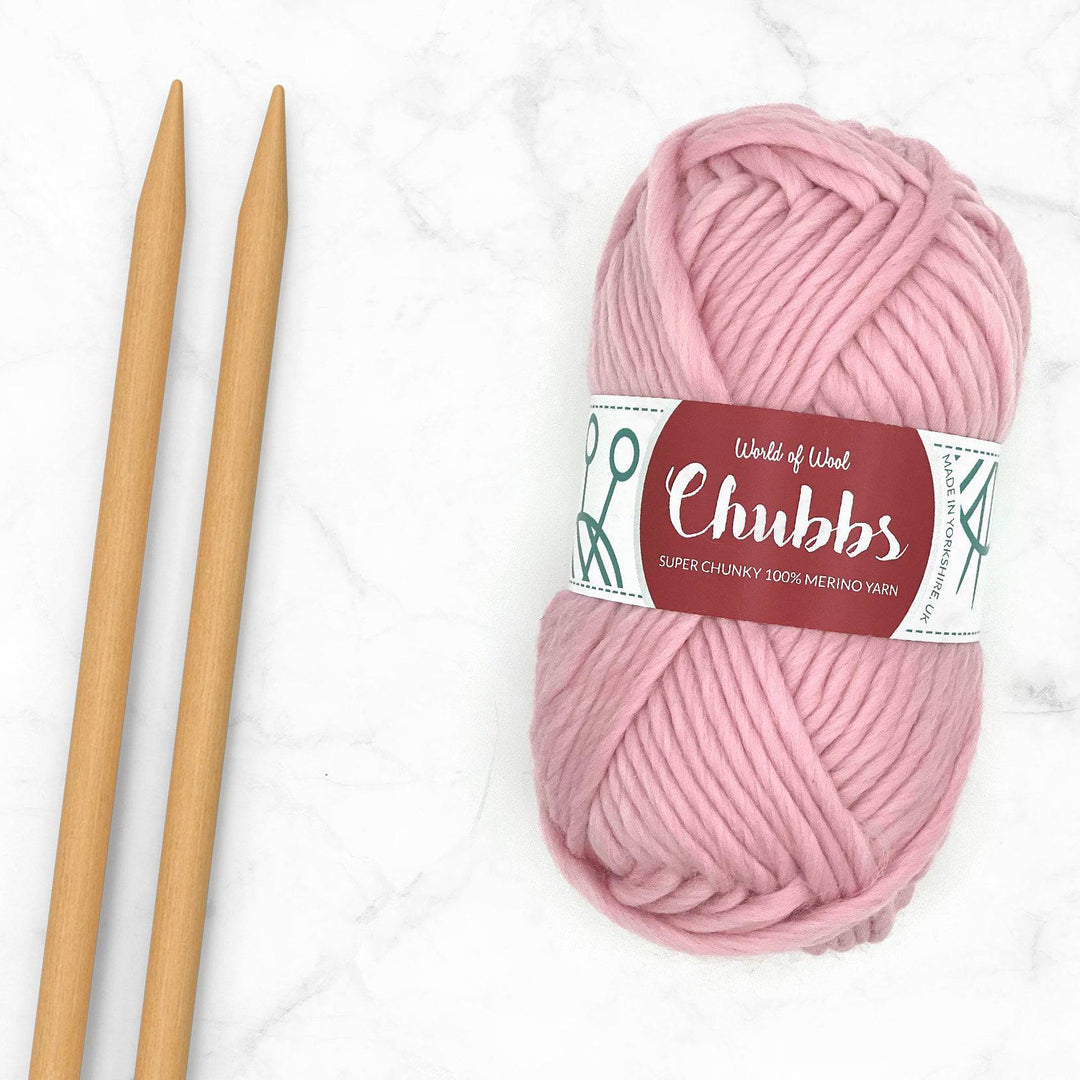 pink candyfloss coloured yarn ball next to some bamboo knitting needles