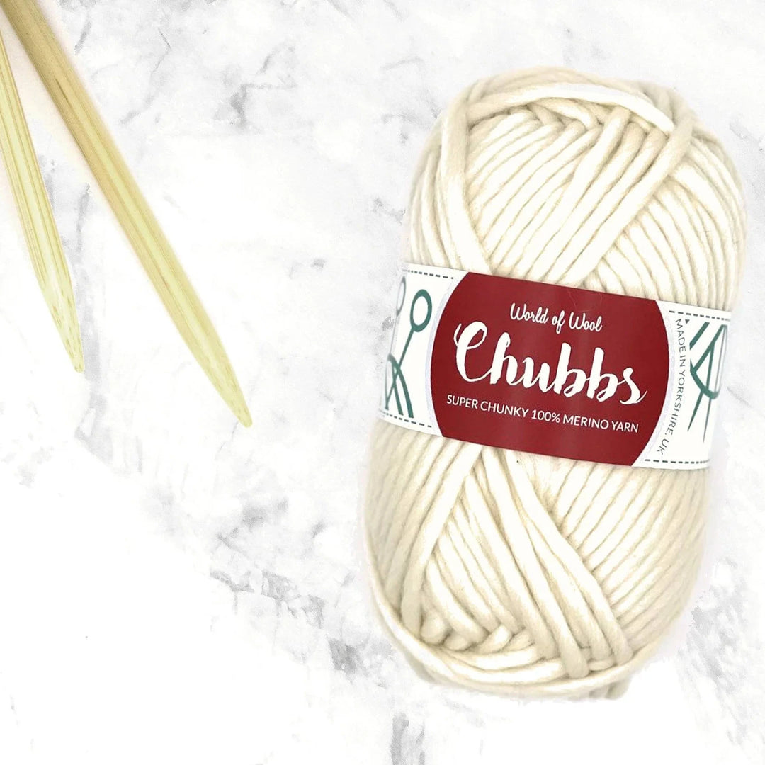 natural white ball of super chunky yarn next to some bamboo knitting needles