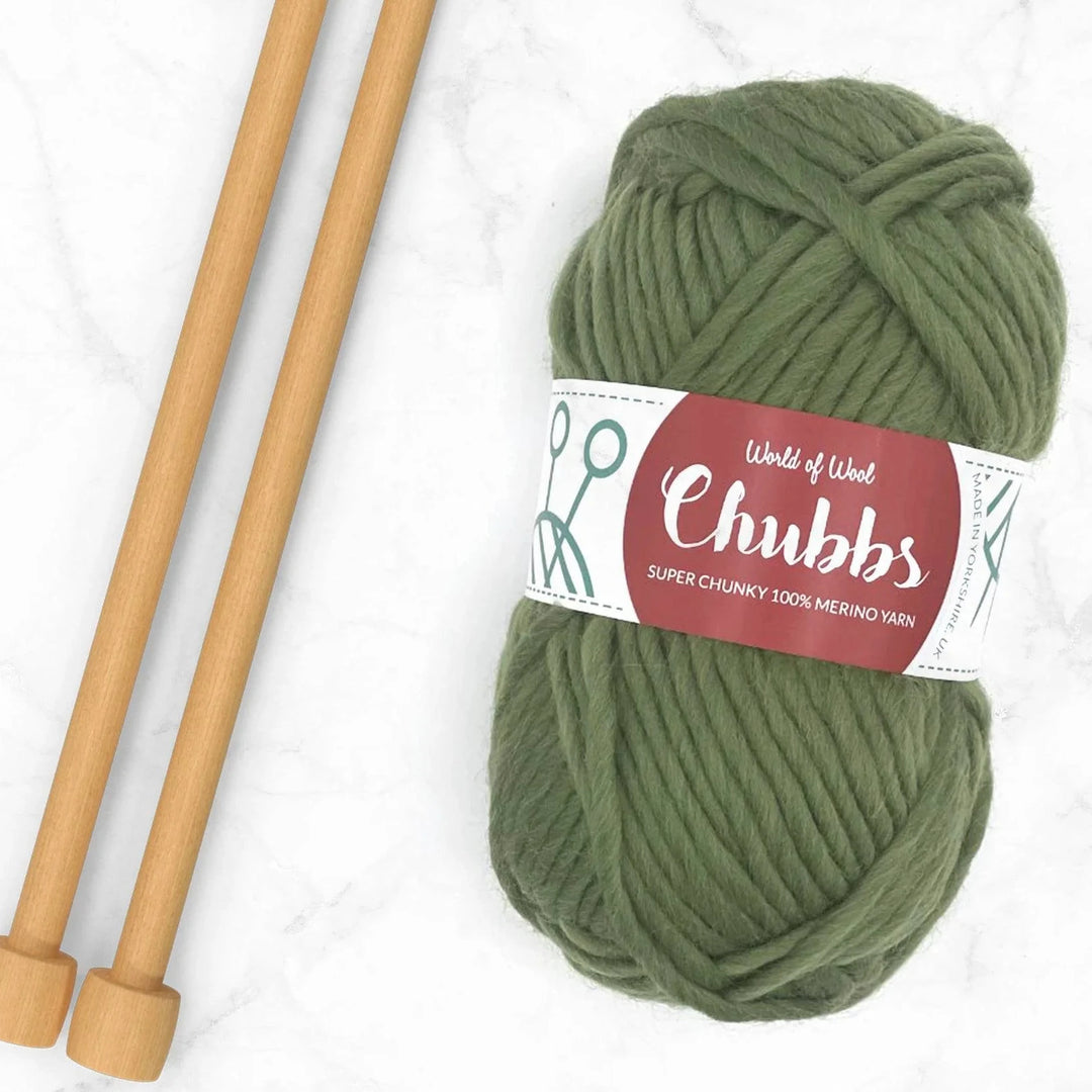 ball of olive coloured yarn next to some bamboo knitting needles