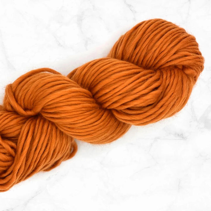 skein of orange super chunky merino yarn on a marble top
